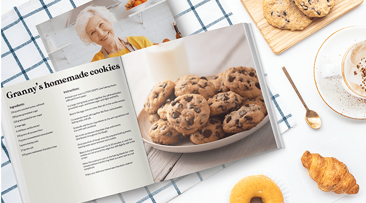 A cookbook is opened at a page showing on one side the recipe to "Granny's homemade cookies" and on the other a picture of cookies piled on a plate