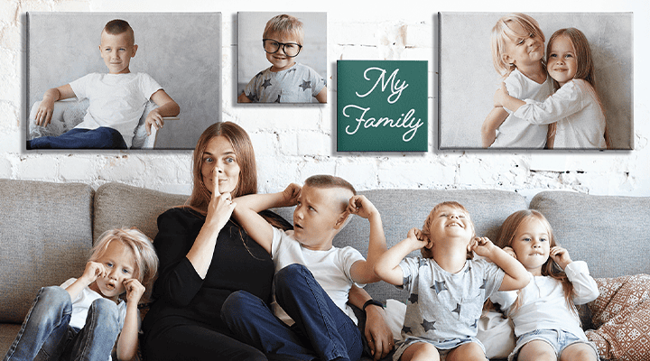 Four young children and their mother are making funny faces while sitting on a couch. The wall behind them is decorated with canvas prints depicting the four siblings