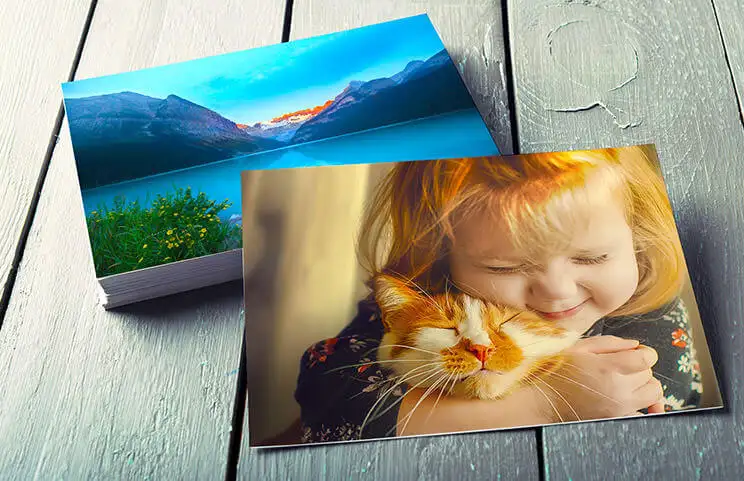 Stack of family photo prints of girl and cat from photo printing service