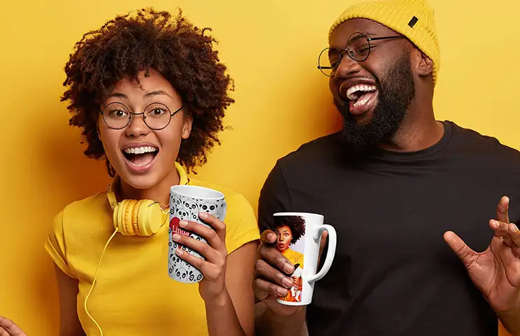 Young couple holding personalised latte mugs with text and images on