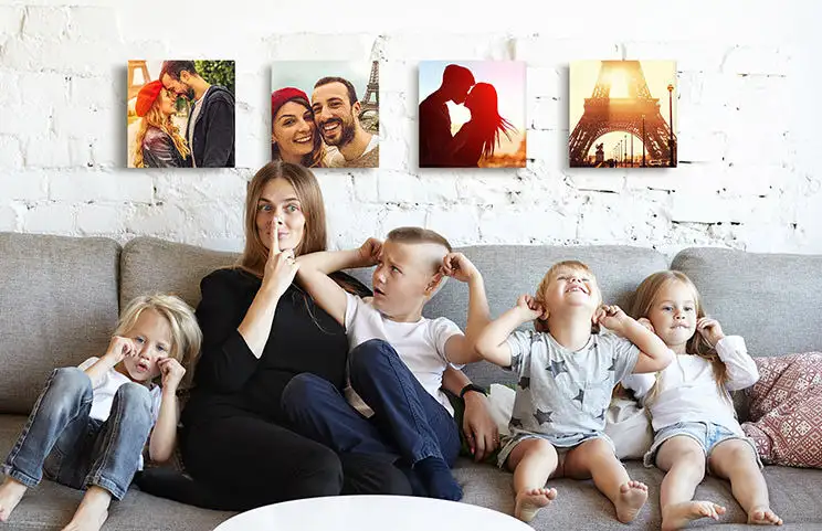 Mom and four young kids sitting on sofa in front of four photo canvases